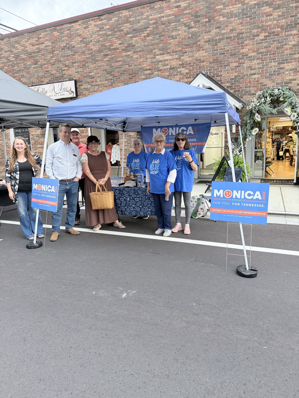 Monica campaign volunteers and supporters gathered under the blue tent at a downtown street festival