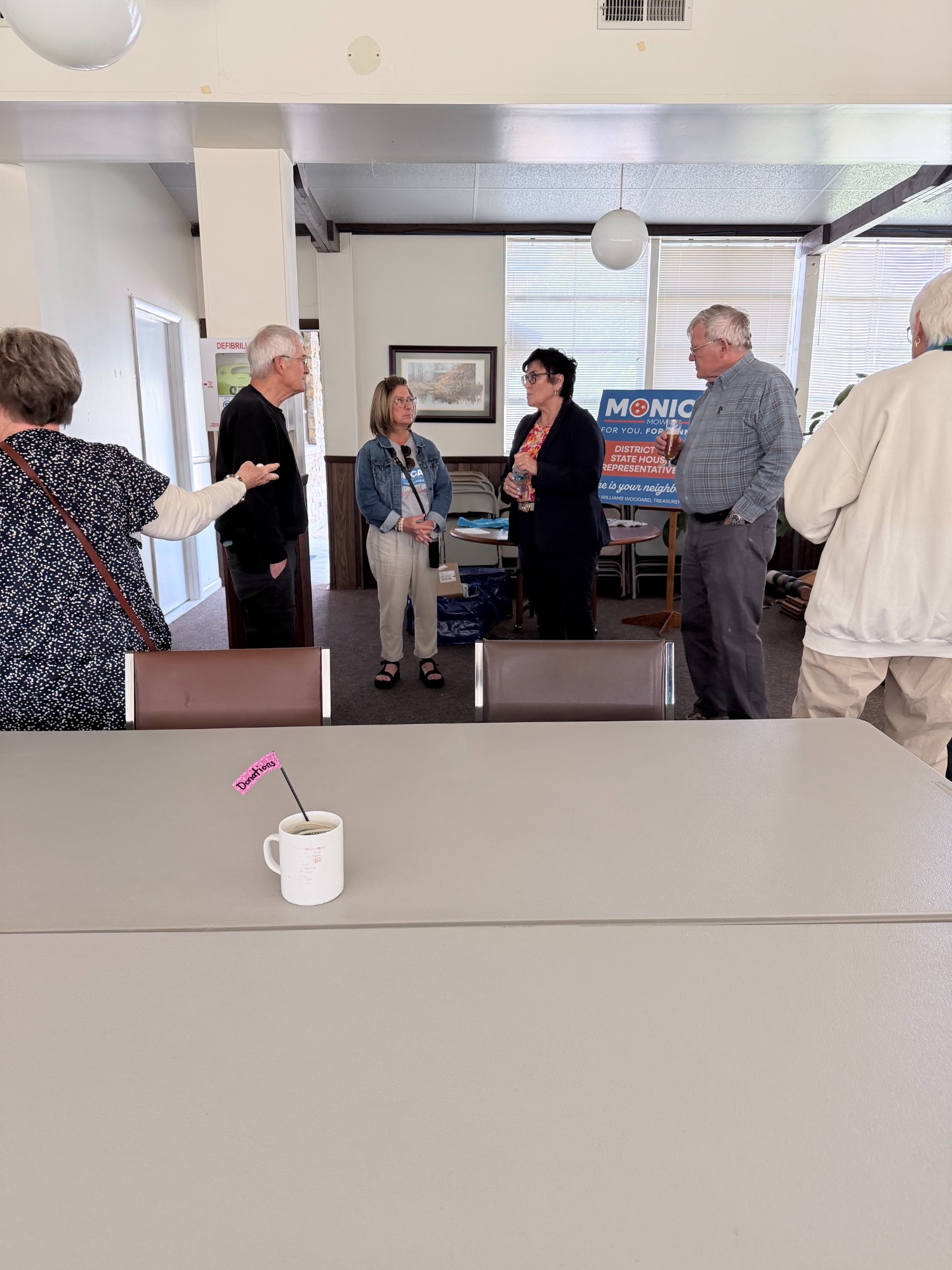 Supporters gathering at a District 25 meet and greet beside a Monica Mowdy yard sign